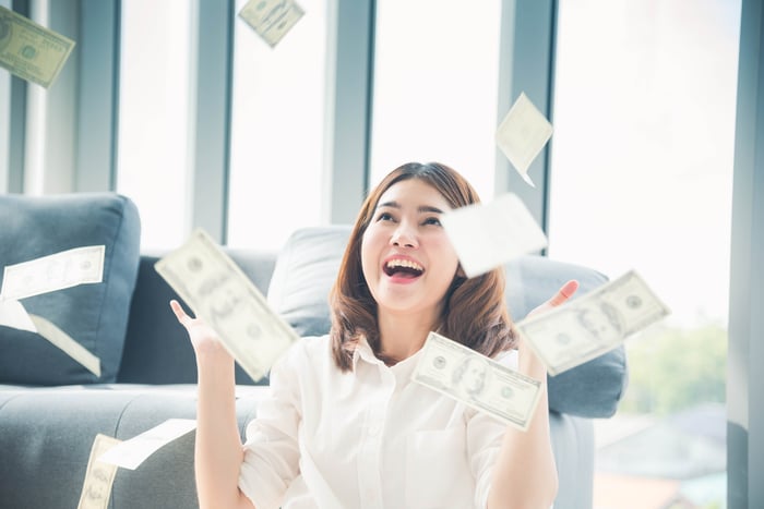 A person celebrating as money rains on them.