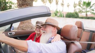 Hip senior couple riding in a convertible on a Florida roadway