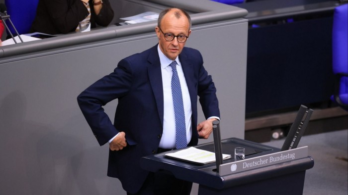 Friedrich Merz stands at a podium at the Bundestag in Berlin