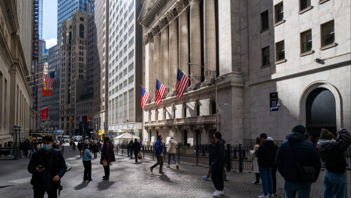 Pedestrians walk down Wall Street