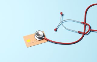 red stethoscope on a peach-colored debit card