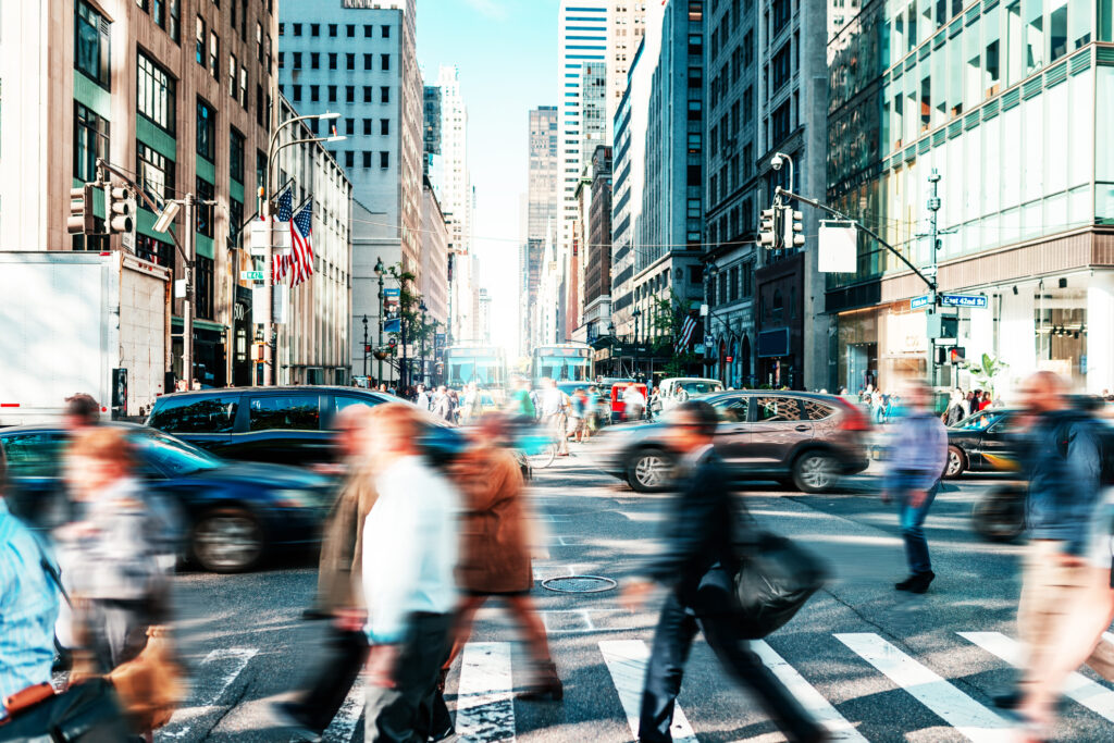 Blurred office workers cross a busy street in New York City.