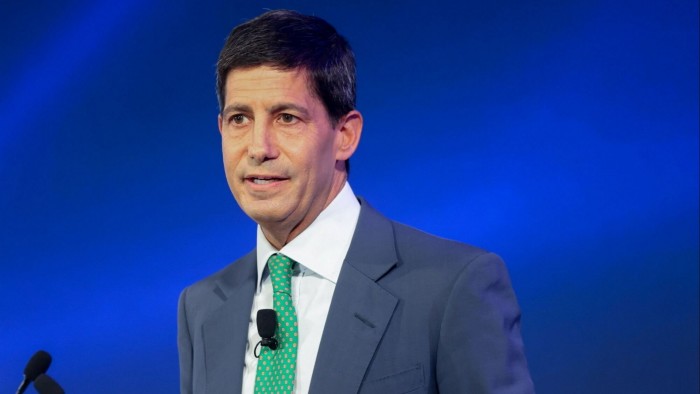 A close up of Kevin Warsh behind a blue background