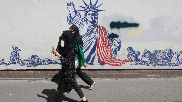 Residents stroll past an anti-US mural on a street in Tehran ahead of talks in Rome