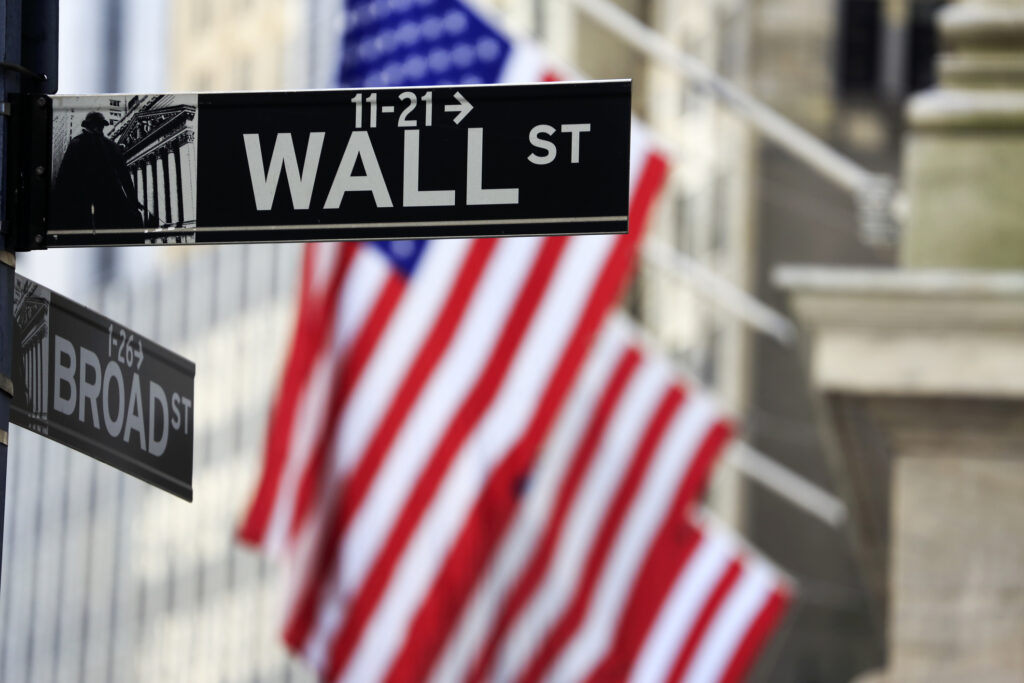 Wall Street and Broad Street street signs in New York City with American flag in the background