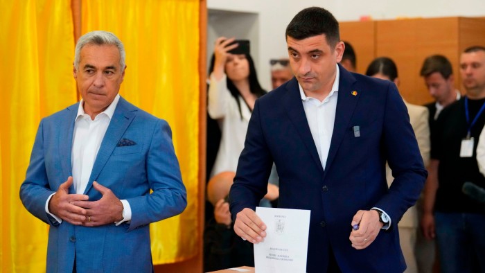 Presidential candidate George Simion, right, casts his vote next to Calin Georgescu