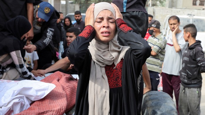 A woman holds her head at a funeral for Palestinians killed in Israeli strikes