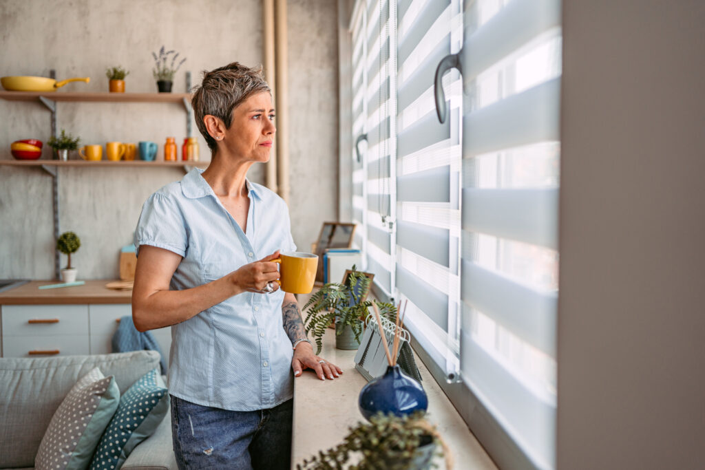 Woman Looking Out a Window and Drinking Coffee