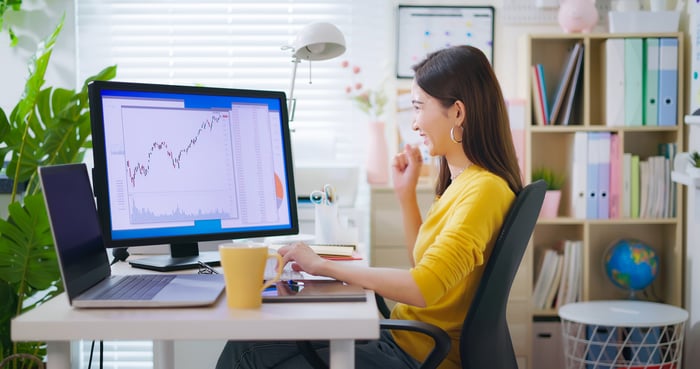 Person smiling and looking at a computer screen with charts.