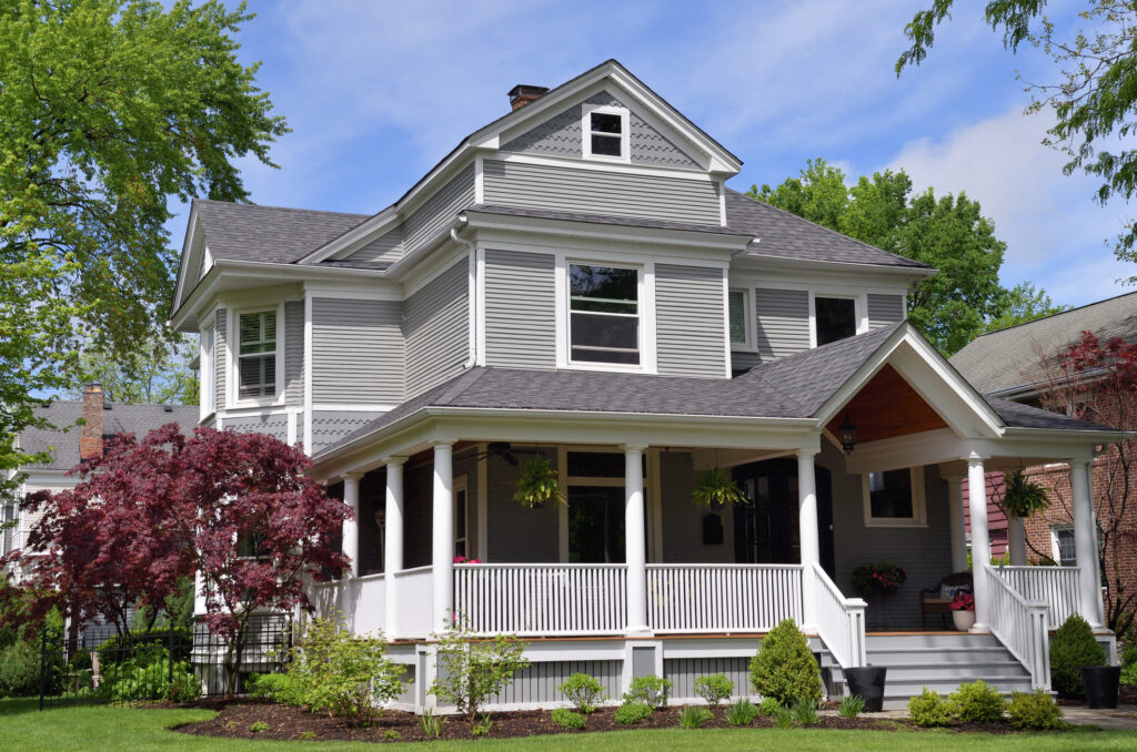 A large, well-kept suburban home with a large garden and front porch.
