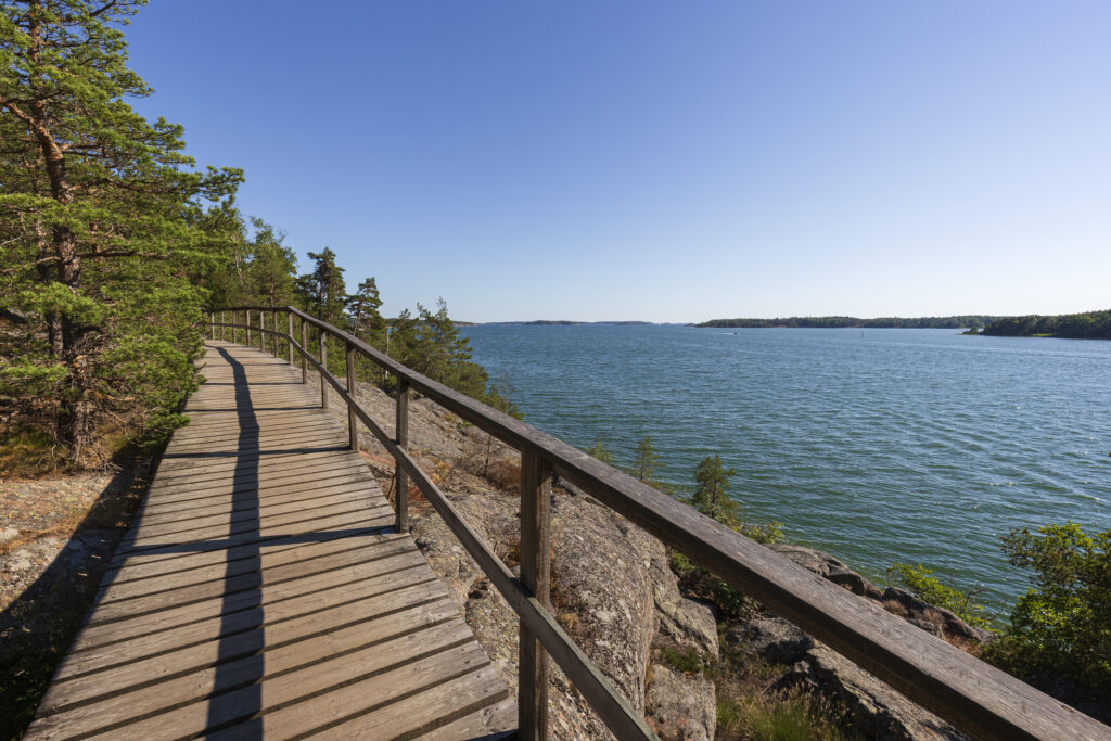 Elevated wooden seaside walkway on a cliff by the Baltic sea in Mariehamn, Åland Islands, Finland, on a sunny day in the summer.