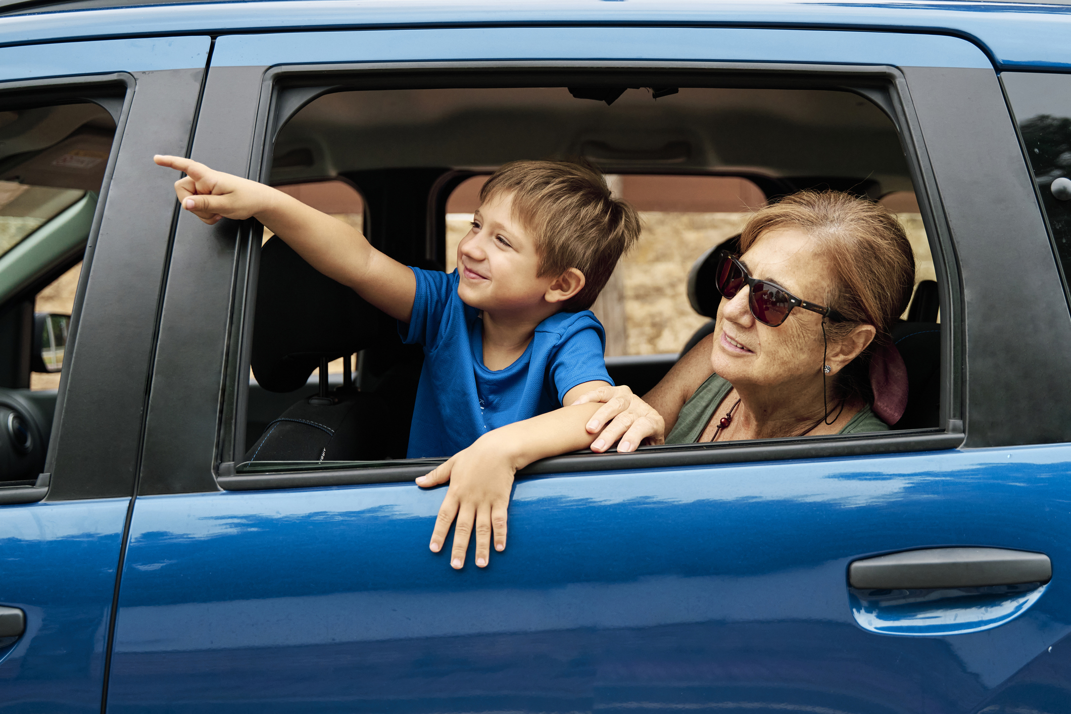 A grandmother and grandson look out at the sites while sitting in a car.