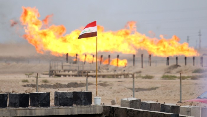An Iraqi national flag flying in front of excess gas as it is being burnt off at an oil refinery near Basra, Iraq