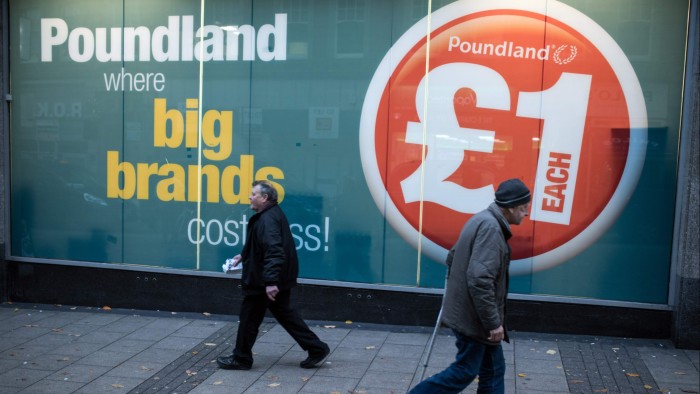 Two men walk past a Poundland discount store in Nottingham