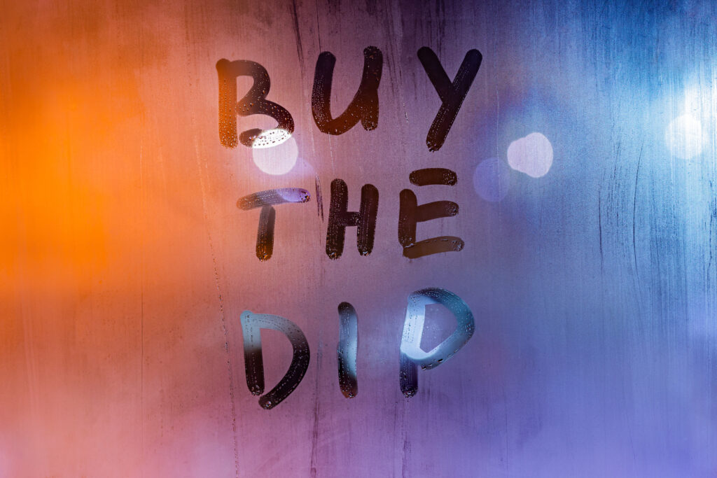 The investing strategy &quot;buy the dip&quot; written on a steamy window.