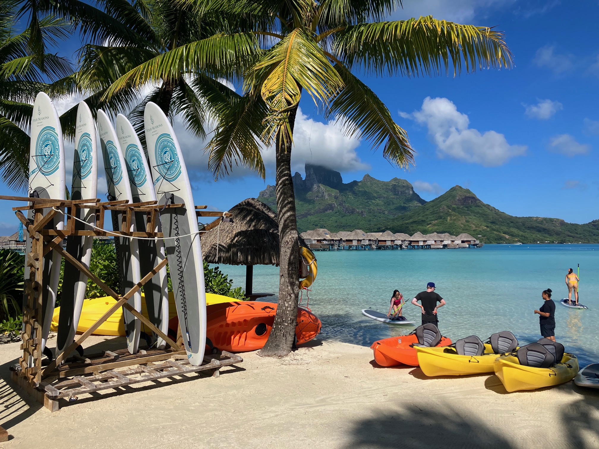 View of paddle board equipmen, kayaks and swimmers at a beach in Bora Bora, French Polynesia.