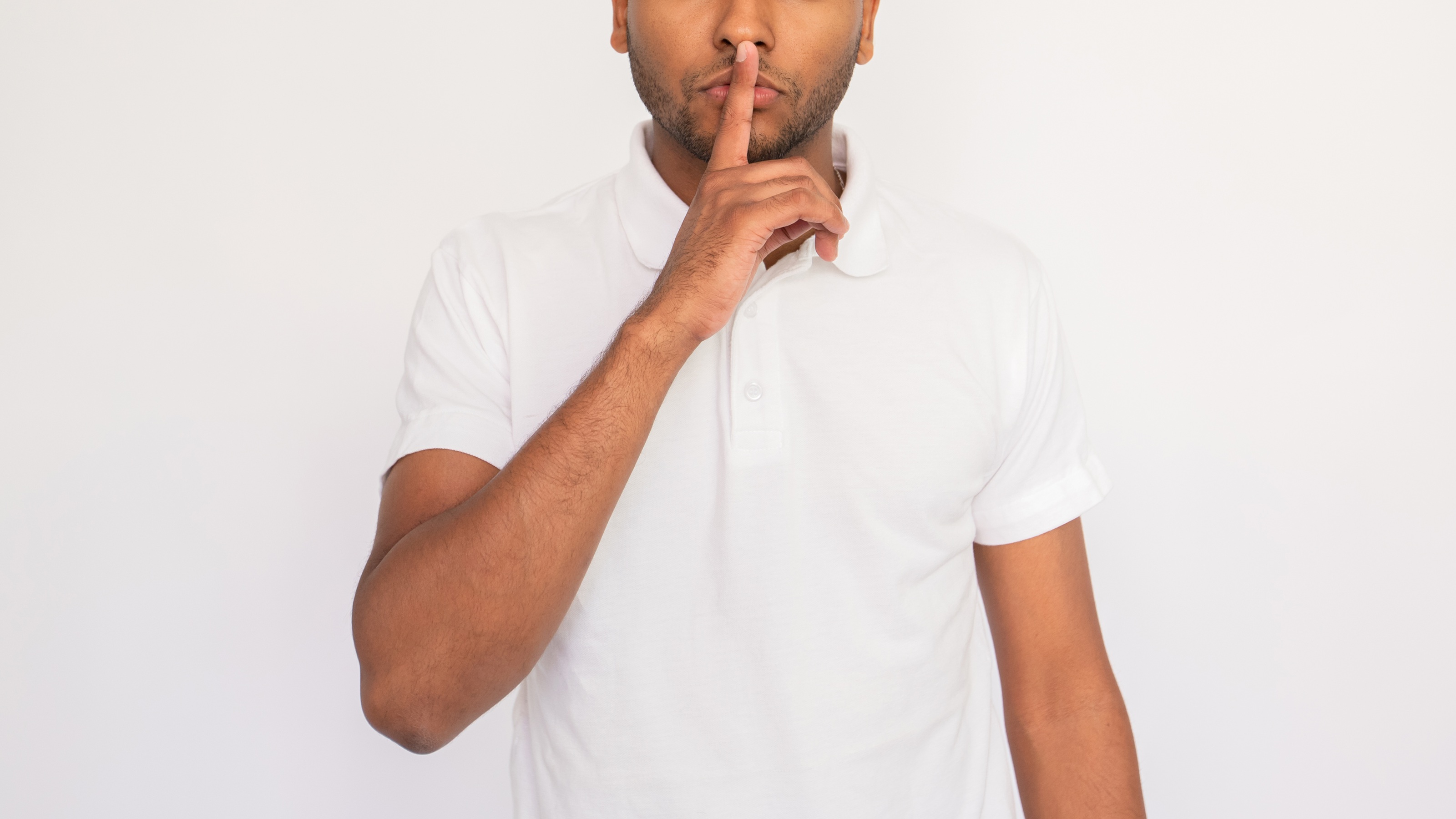 A young man makes the shhh gesture.