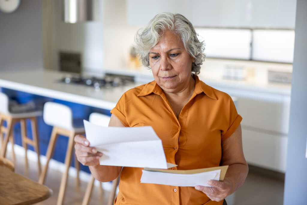 Senior Latin American woman at home reading a letter she got in the mail &acirc; domestic life concepts