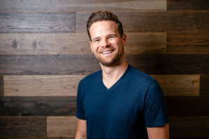 Andy Hill wearing a blue shirt and posing for the camera. He is the host of Marriage, Kids and Money podcast where he shares how he saved up and can now do part time work without sacrificing his financial status.