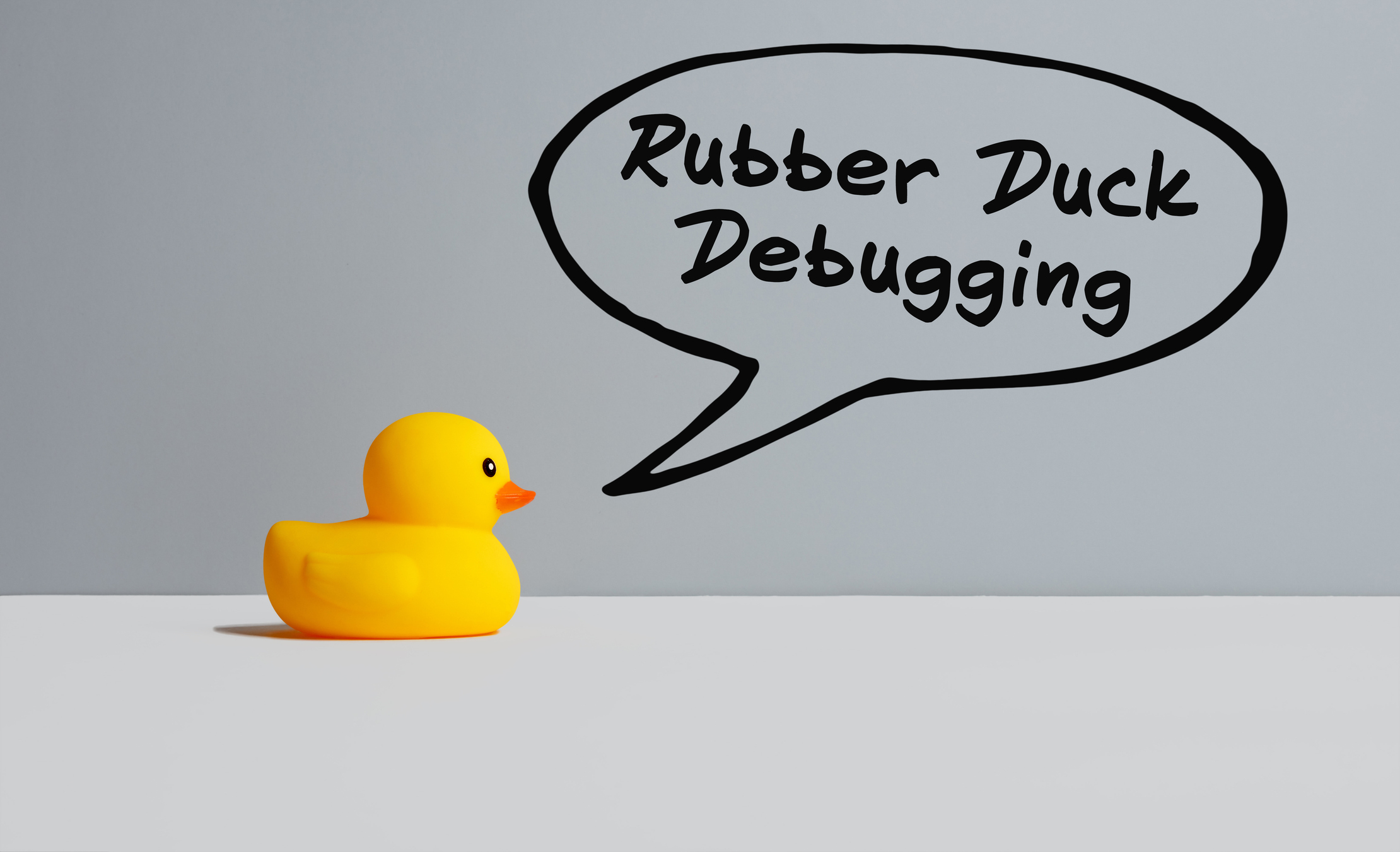 a rubber duck on a gray background with a speech bubble that reads "rubber duck debugging"