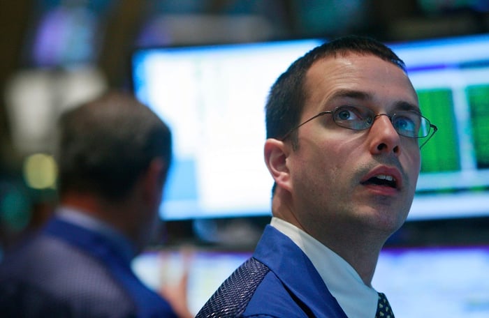A New York Stock Exchange floor trader looking up in awe at a computer monitor. 