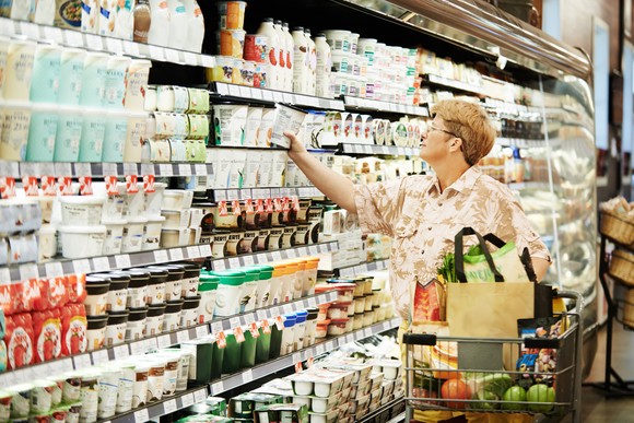 A woman checks prices in the dairy section of a grocery store.