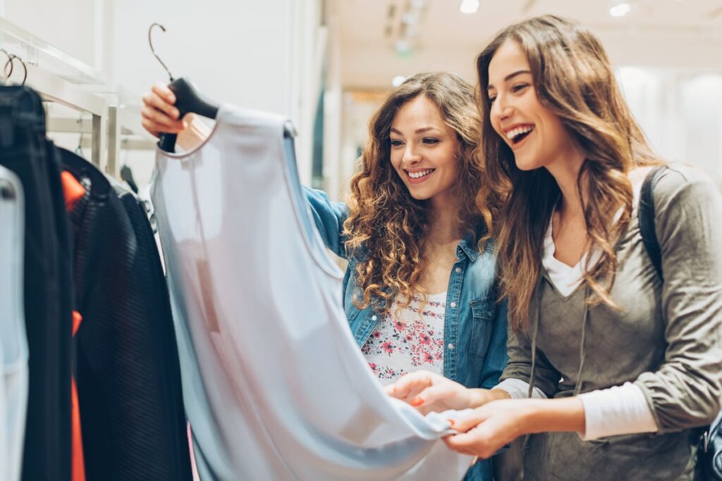 People are smiling while shopping inside a clothing store.