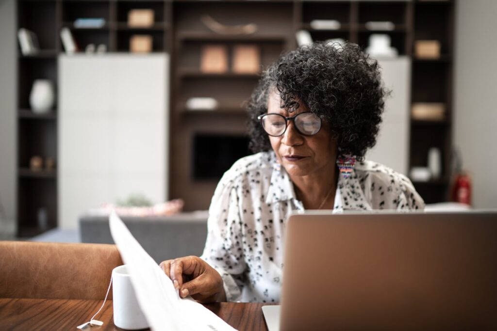 Adult typing and looking at financial paperwork.