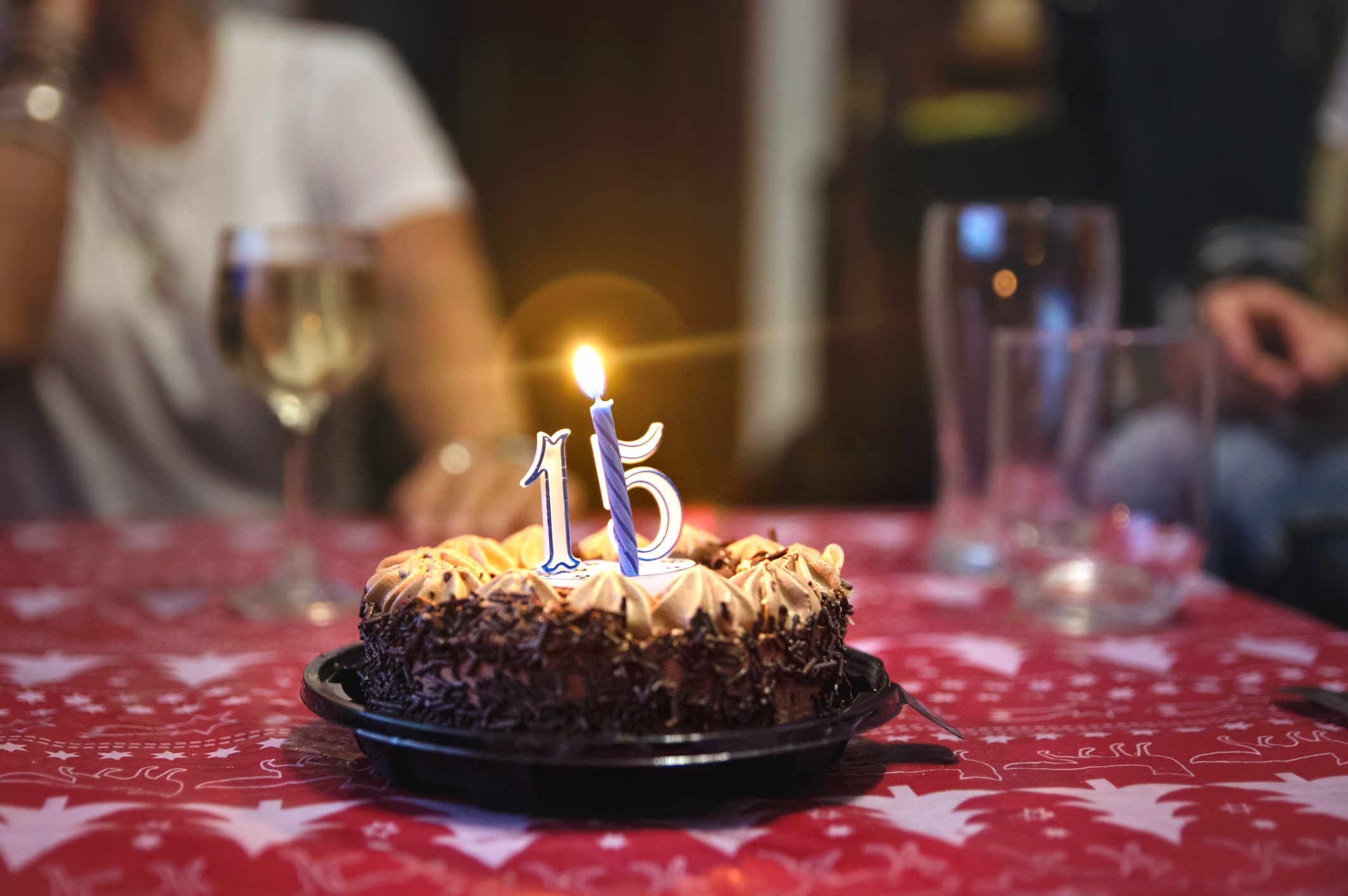 A chocolate cake on a table with a candle and the number "15."
