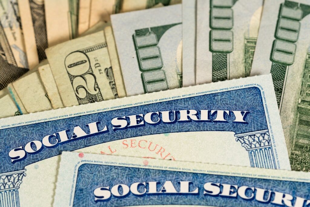Two Social Security cards with piles of cash under them,