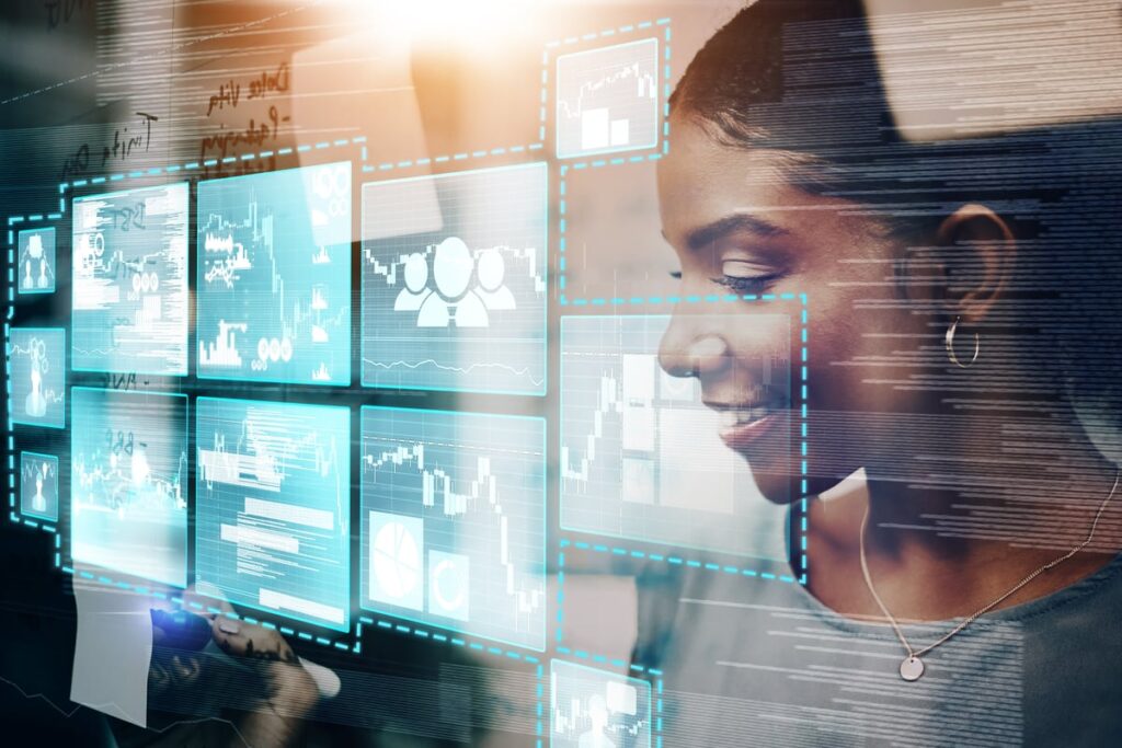 A person looks into the reflections of multiple computer screens.