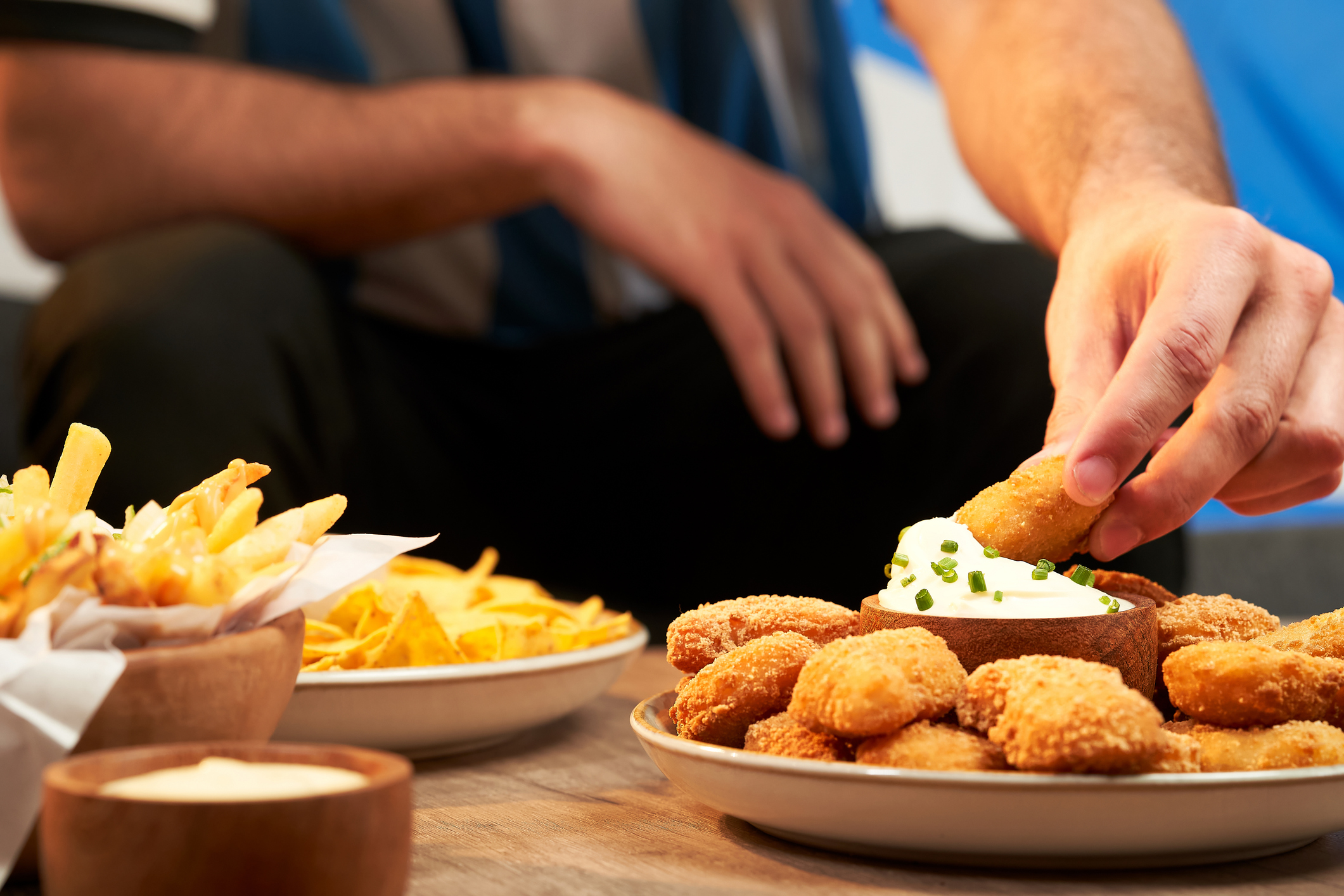 Football fan eating snacks served on a wooden table