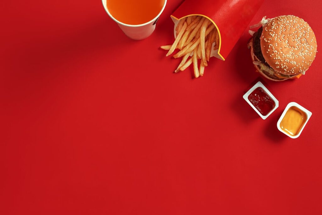 French fries, a burger, and a drink on a red table.