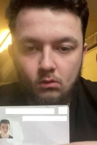 Dylan Earl holds up his passport, showing his photo and personal details.