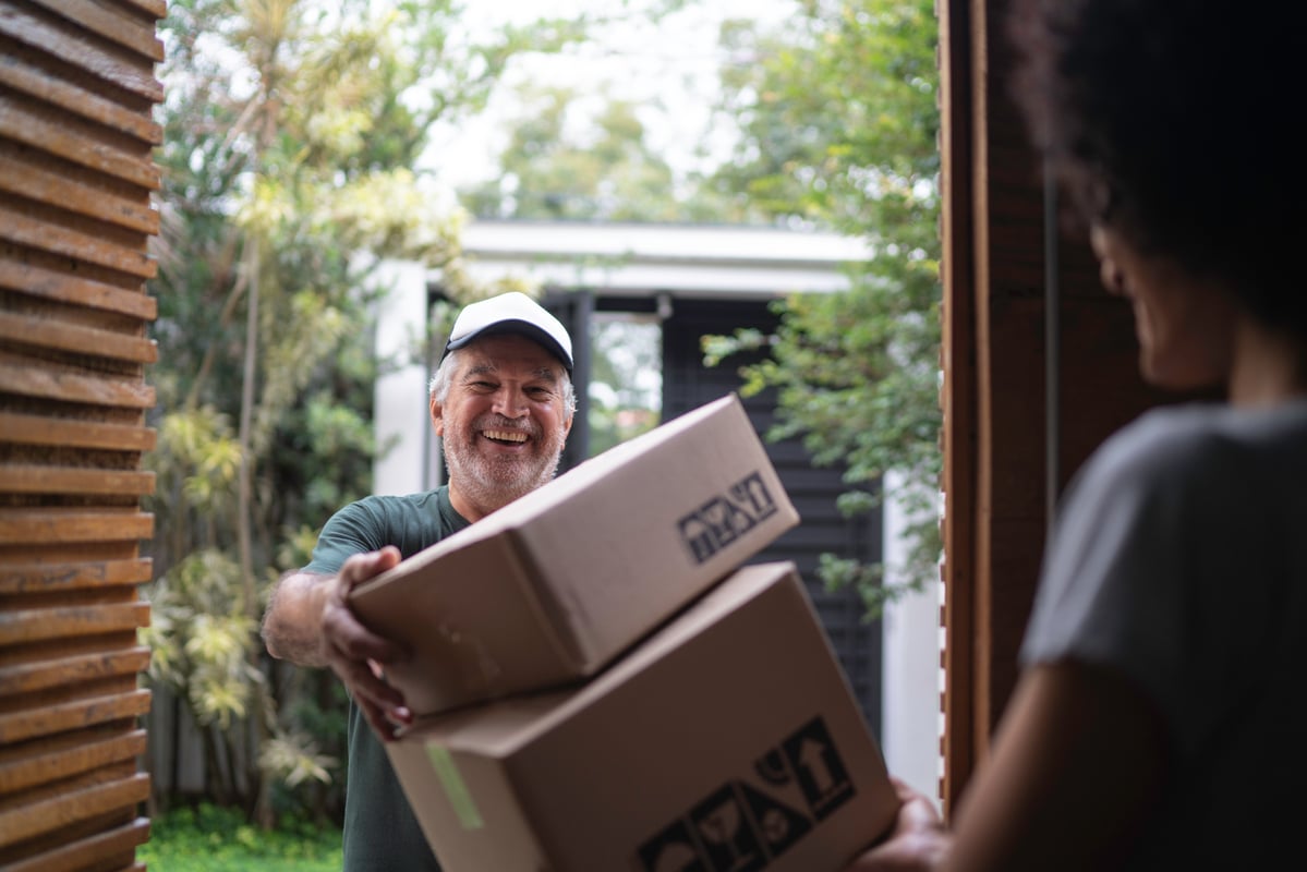 A parcel delivery service driver hands packages to a customer.