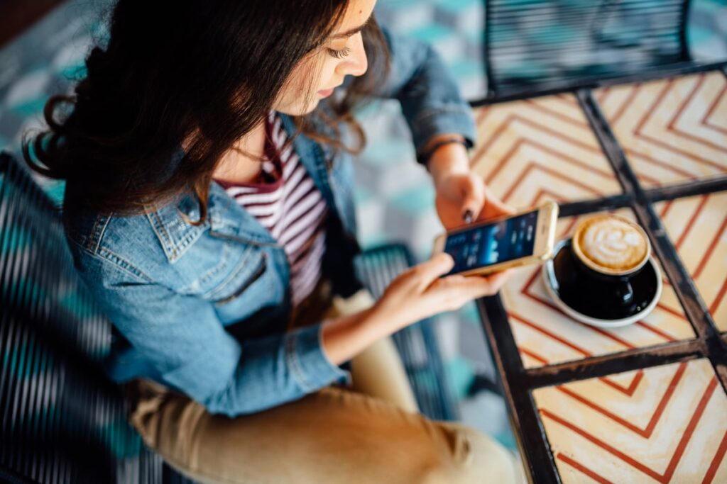 A person enjoying a cup of coffee while looking at a phone.