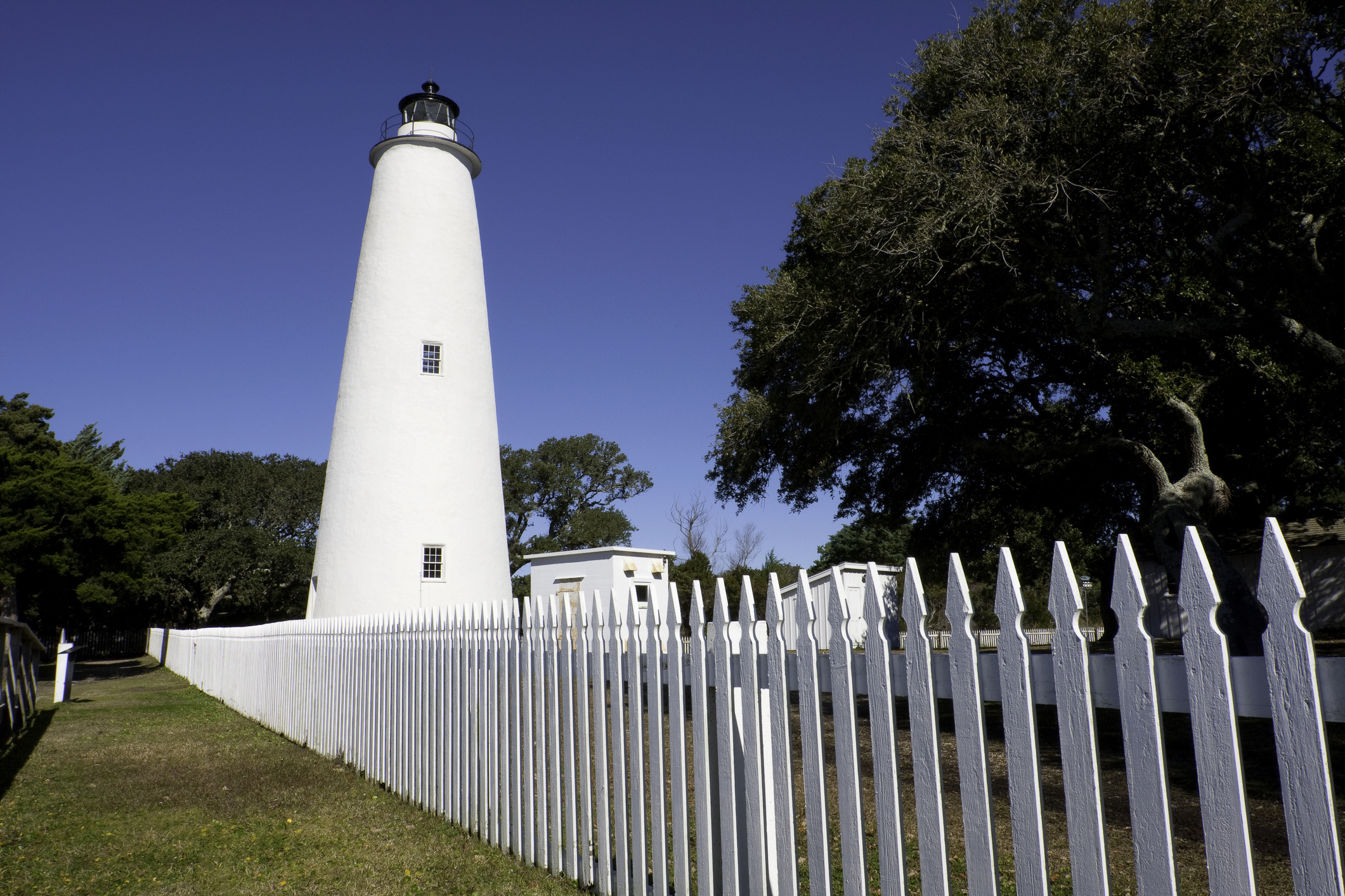 The Ocracoke Island white Lighthouse on the Outer Banks in North Carolina, with a picket fence
