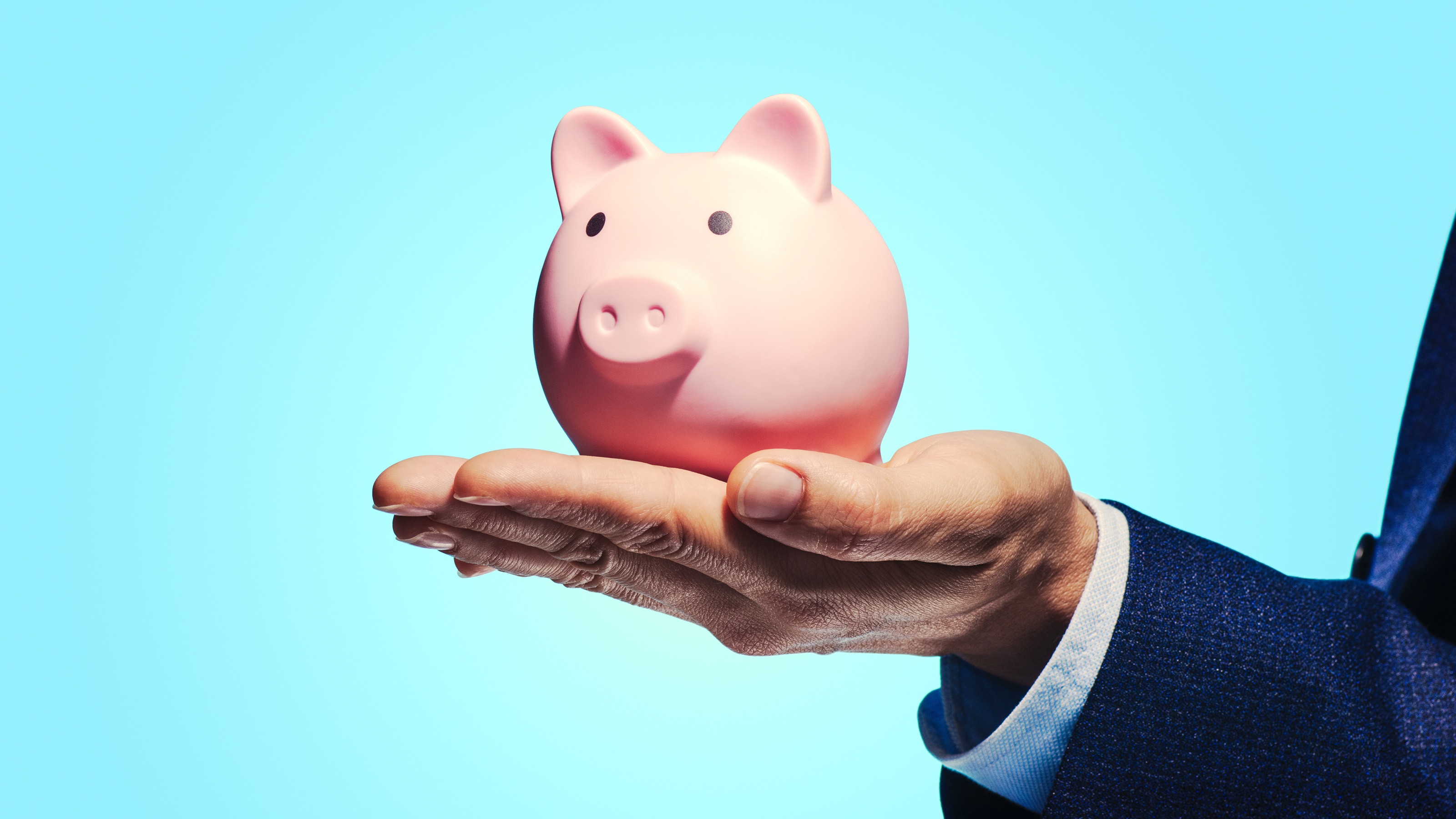 A piggy bank sits on a man's hand.