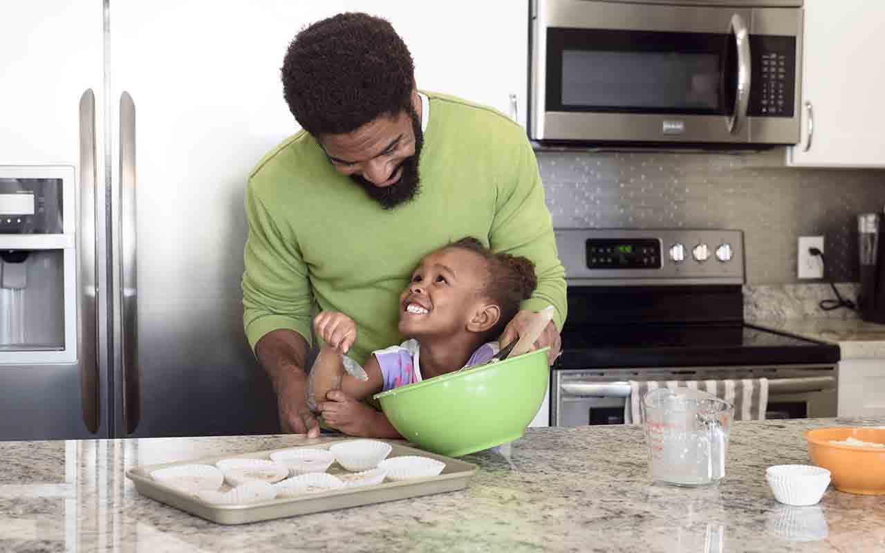 Small child learning to bake with her dad