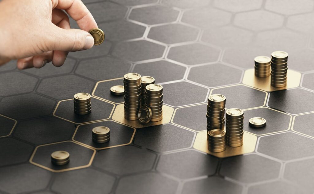A hand placing piles of coins on a grid.