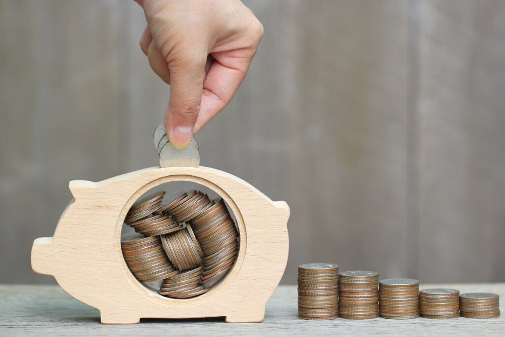 Someone putting coins in a piggy bank.