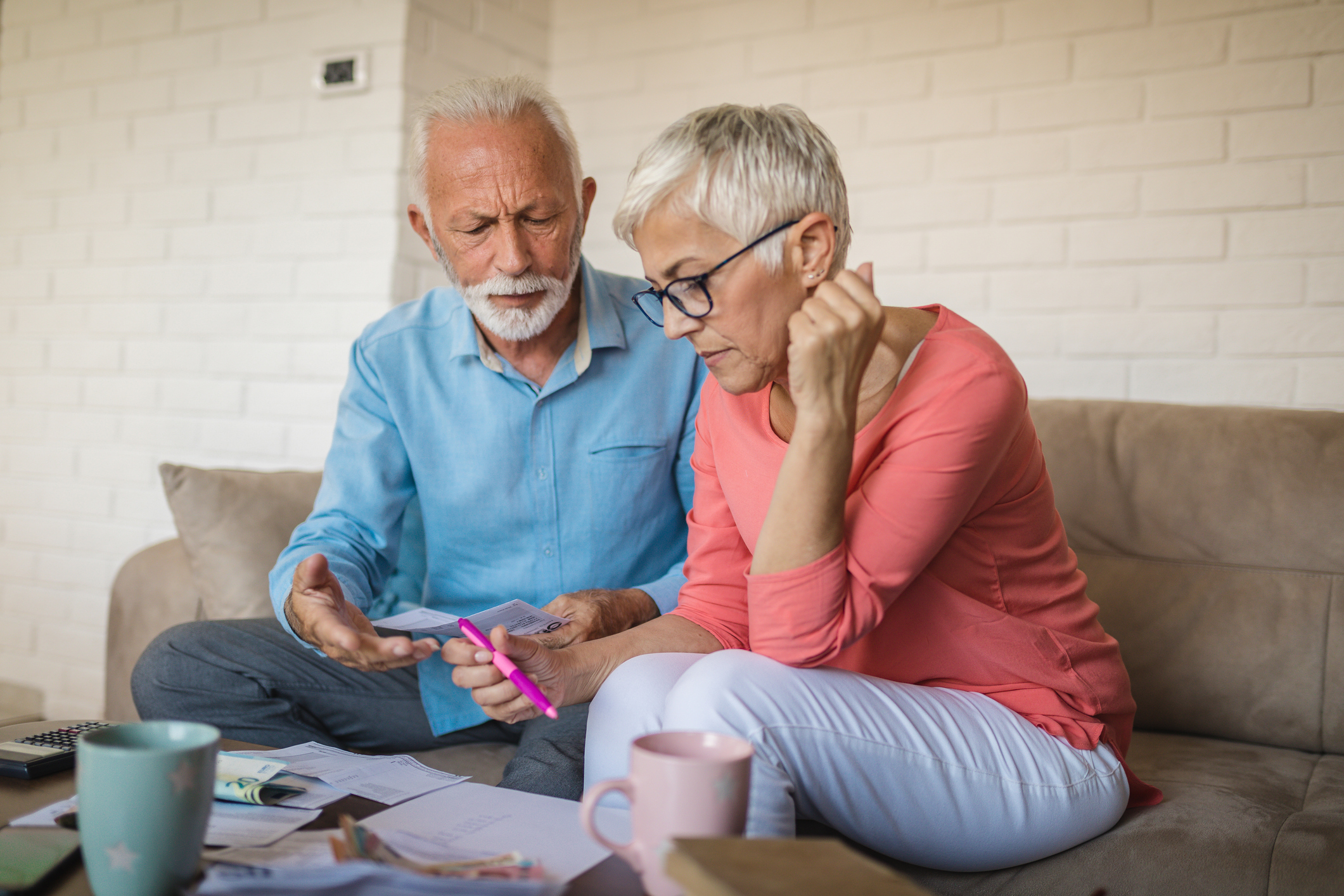 Senior couple having a hard time at home, calculating incoming bills and debt.