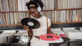 A young woman wearing headphones browses vintage vinyl records in a store.