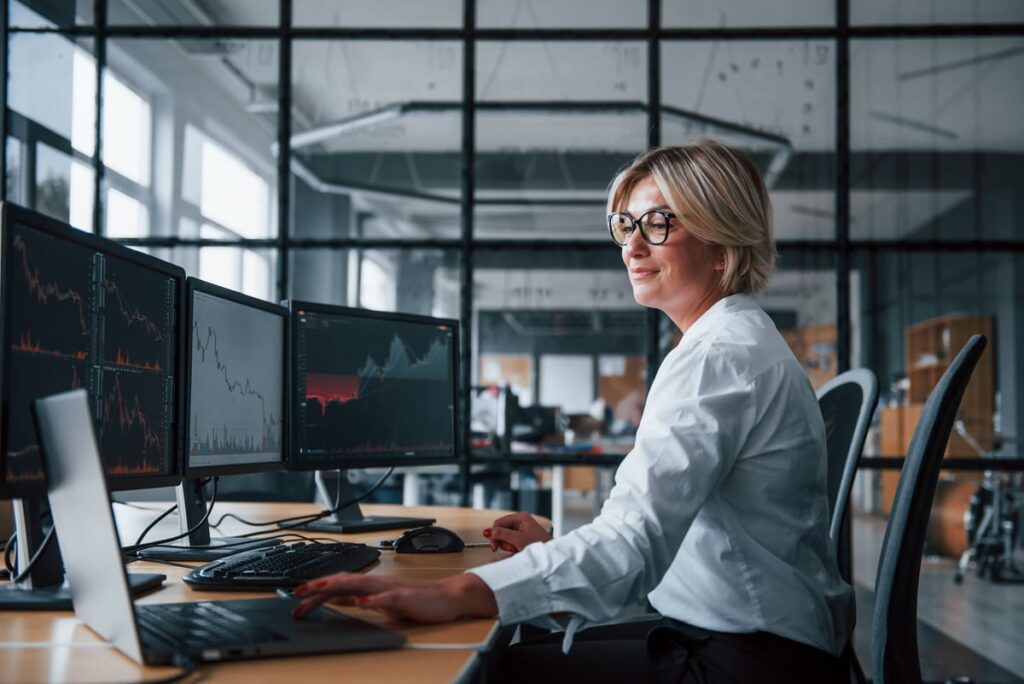 An investor checks stock charts across three monitors.