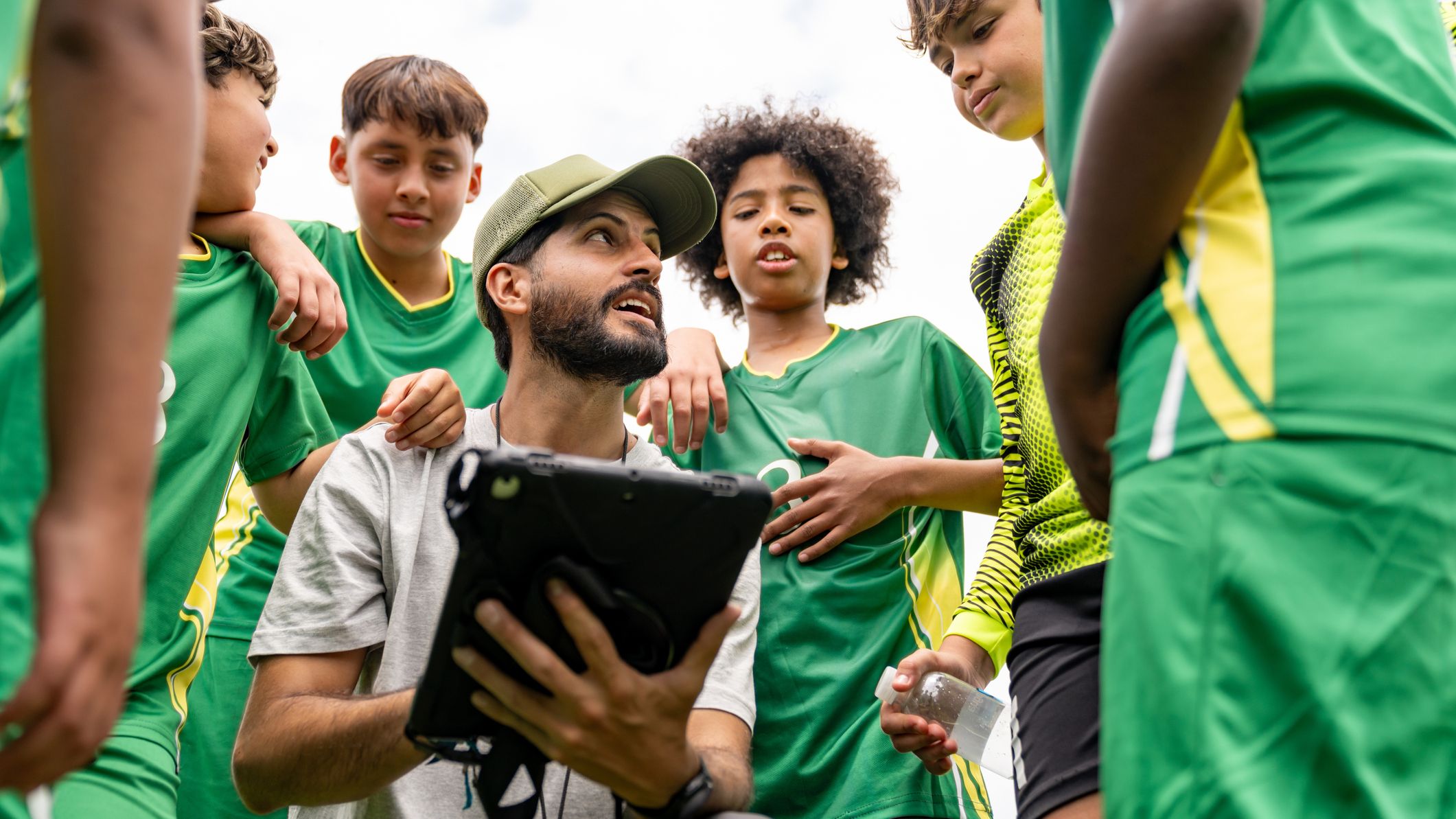 Football coach talking to a group of kids during practice