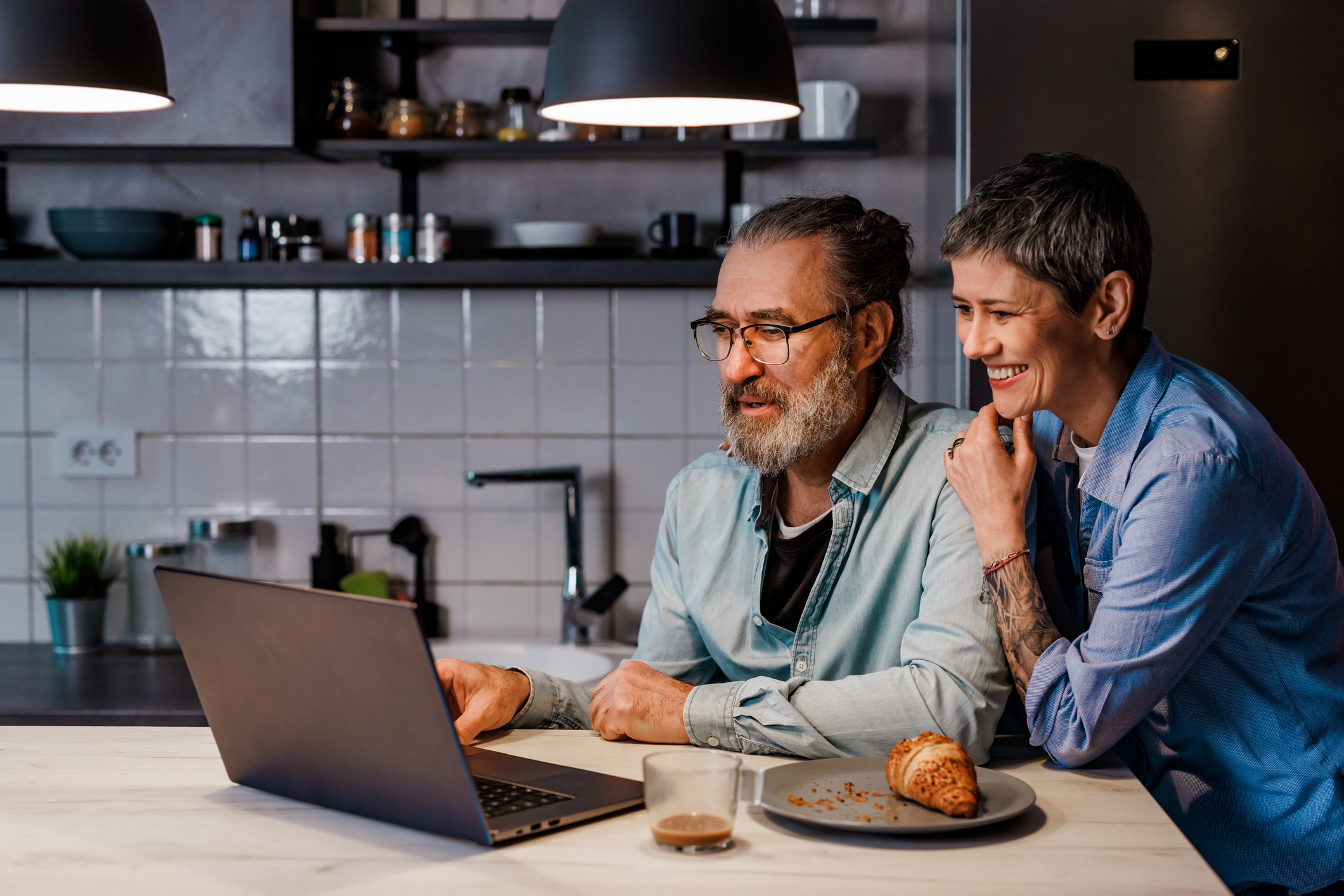 Mature couple using laptop during breakfast at home