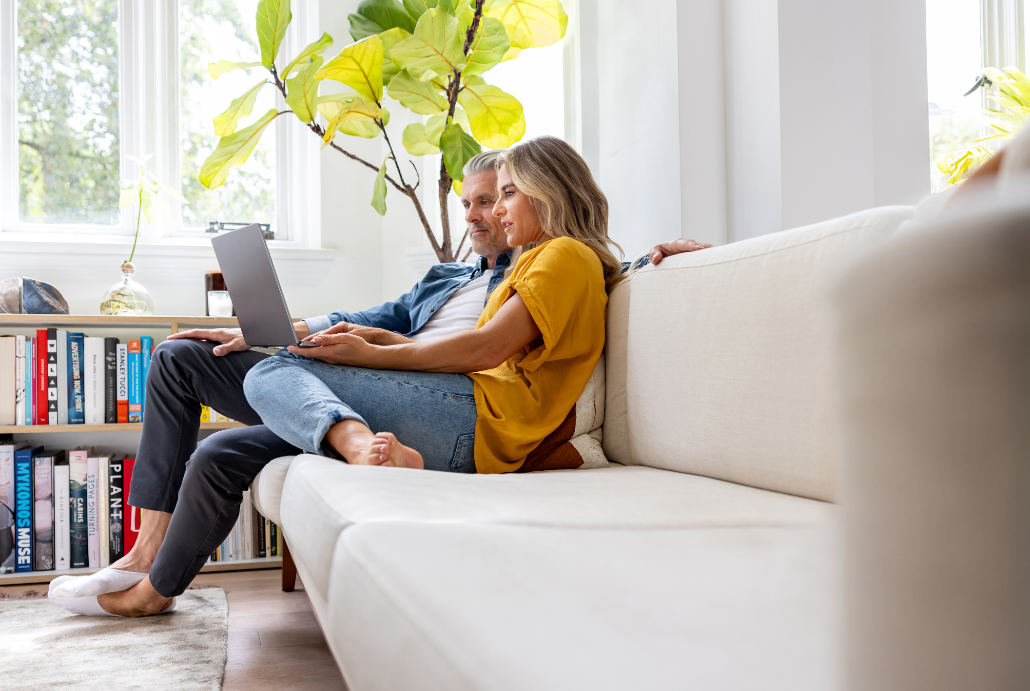 Happy couple at home booking a reservation online using a laptop computer &ndash; lifestyle concepts