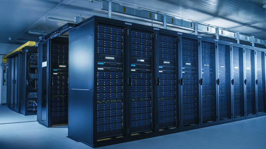 Image shows rows of server racks inside of a data center facility.
