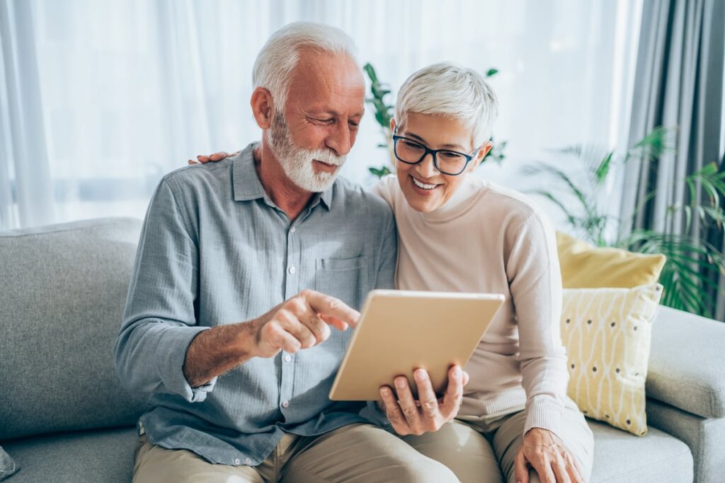 Two smiling people looking at a tablet.