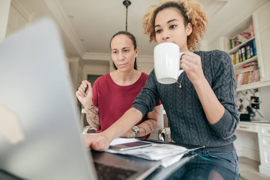 Two investors at home look at something on a laptop screen.